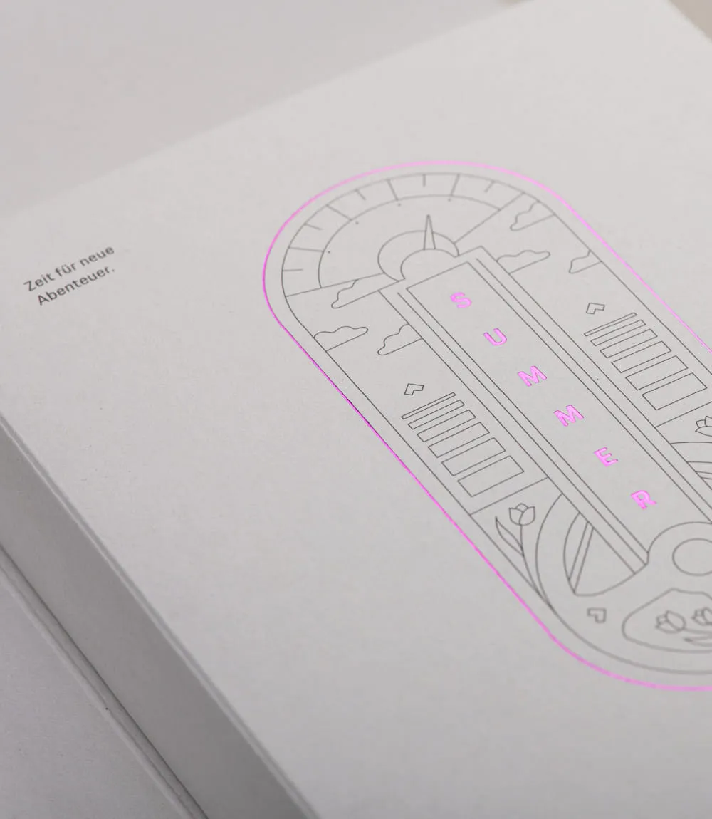 Detailansicht der Mailing-Verpackung für das Porsche Zentrum Olympiapark München mit grafischer Illustration und pinker Heißfolienprägung SUMMER. Links der Text Zeit für neue Abenteuer.