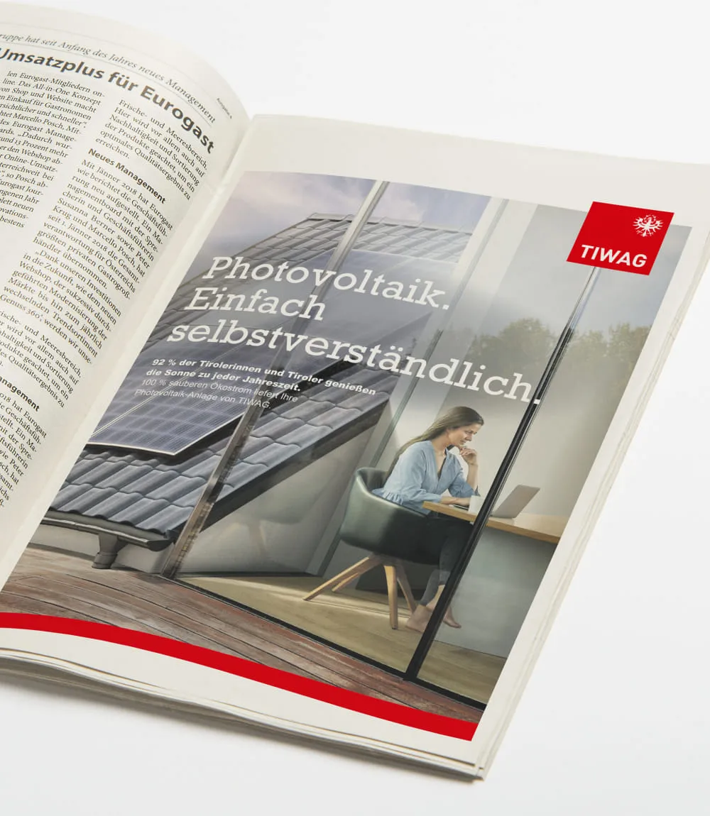 TIWAG-Werbeanzeige in einer Zeitschrift mit dem Slogan Photovoltaik. Einfach selbstverständlich und einer Frau am Laptop neben Photovoltaikanlagen auf dem Dach.